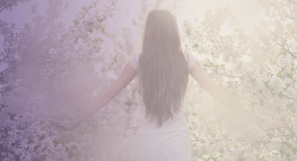 Frau nach Spinal Energetics Behandlung fühlt sich frei in mitten der blühenden Bäume und Wiesen